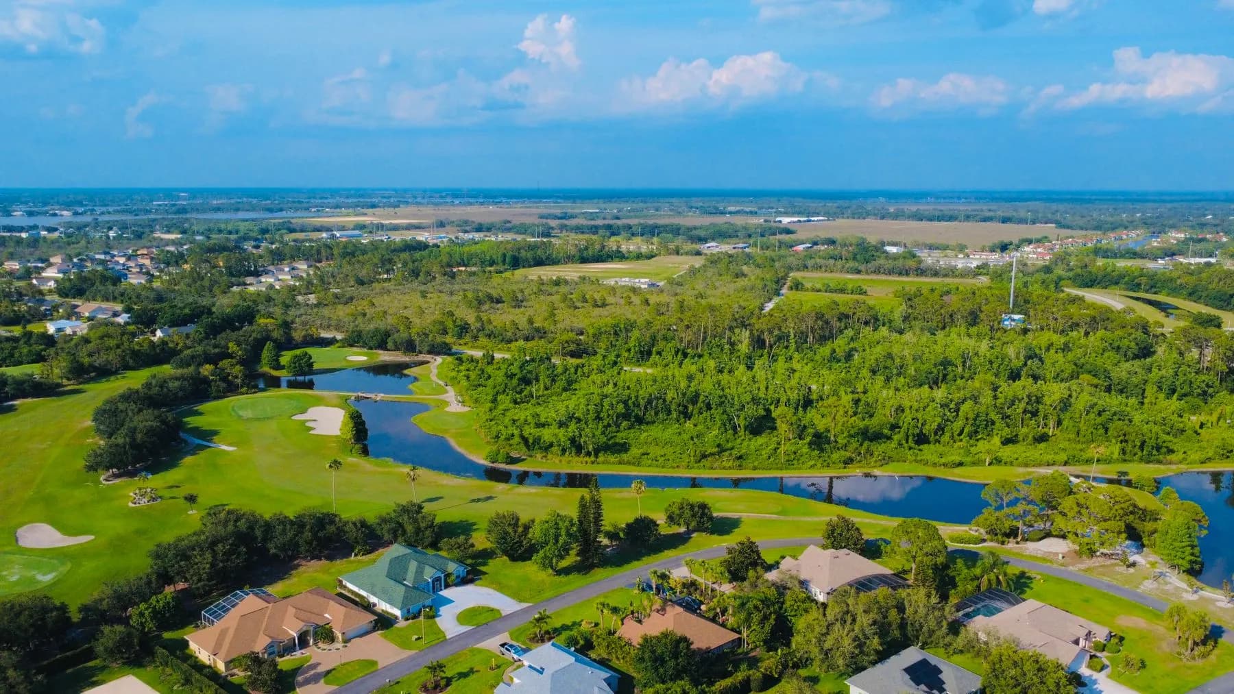 Aerial view of a Florida golf course community with homes, water and trees