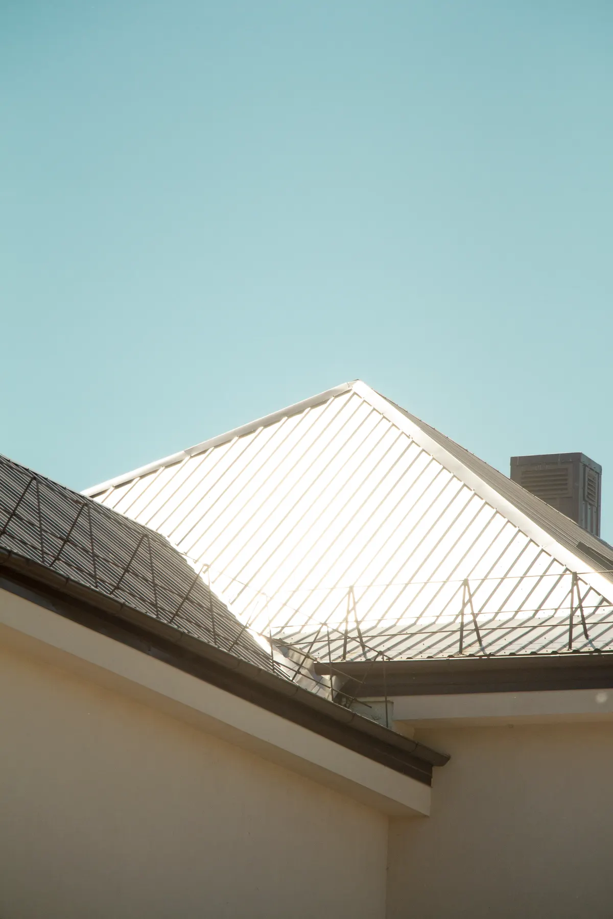 Standing seam metal roof on a white building against a blue sky