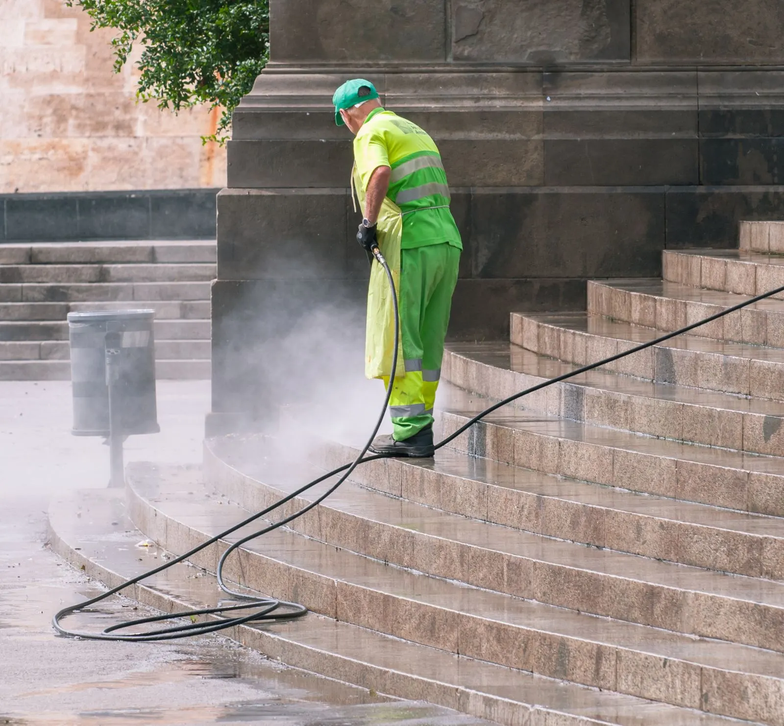 Worker in high visibility gear pressure washing a flight of stone steps